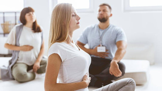 male and two females doing yoga in a relaxed setting