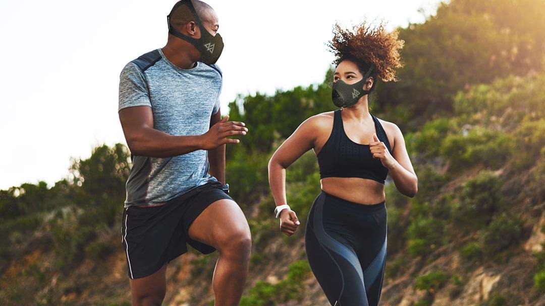 a male ang a female running on a sunset at the trail with their trainingmask