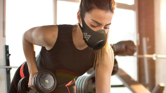 a woman on the gym holding a dumbell with a trainingmask 3.0
