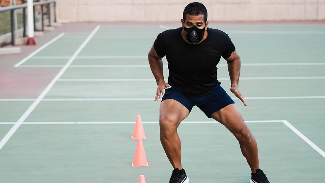 a male athlete doing cone excersice with a trainingmask on